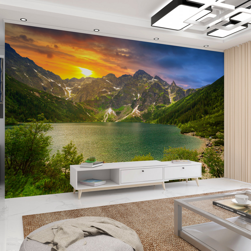 Fototapeta jasny zachód słońca za kamiennymi górami nad jeziorem